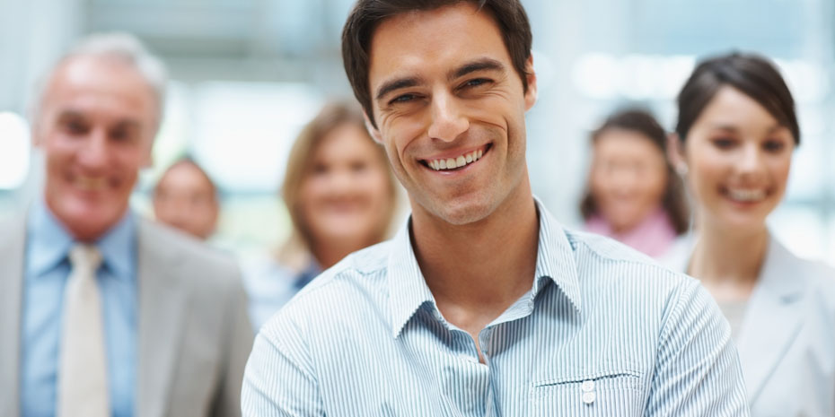 Confident young business executive with his team in the background